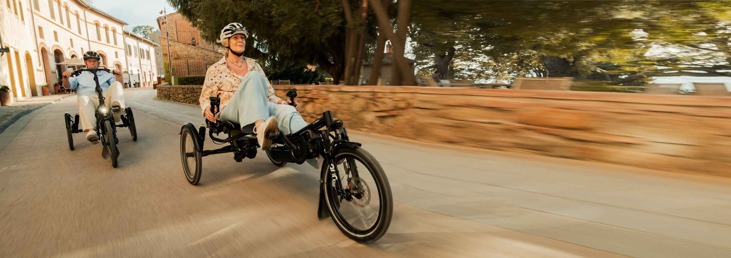 Älteres Ehepaar sitzen beide in einem Seniorendreirad und fahren durch eine italienische Stadt